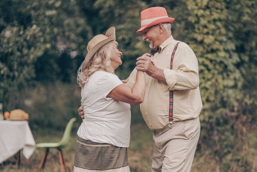 Older couple dancing together in a garden — celebrating life and the people they love