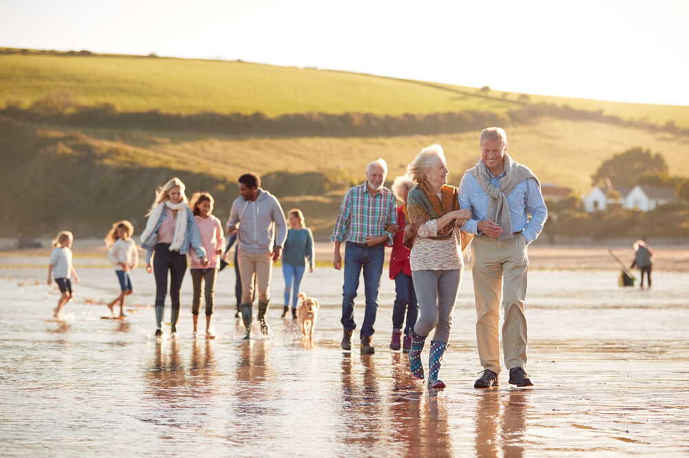 Multi-generational family walking together on a beach at sunset — protecting wealth across generations